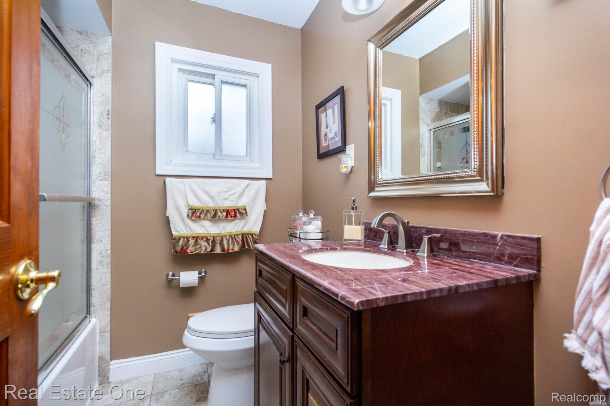 220 Winry Drive Rochester, MI 48307 - Photo 17 of 35 Bathroom featuring a dark wood-finish vanity with an integrated sink and a richly veined countertop