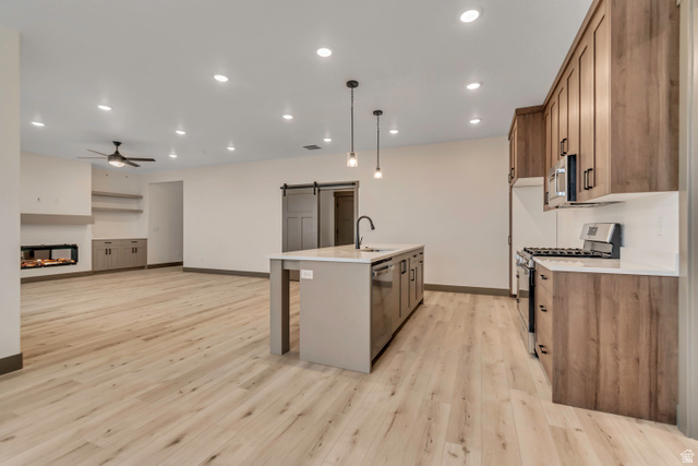 3317 South 1000 West, Unit 6010 Logan, UT 84321 - Photo 34 of 34 Kitchen with a barn door, stainless steel appliances, open floor plan, a kitchen island with sink, and light stone countertops