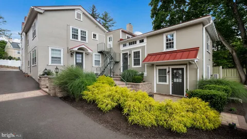 a view of a white house with large windows and flower plants