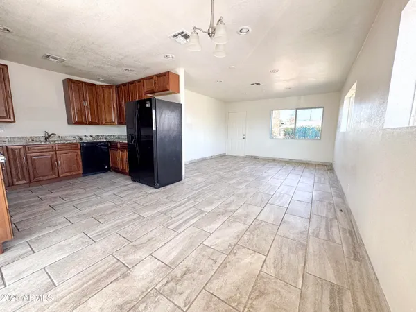 a view of a refrigerator in kitchen and an empty room