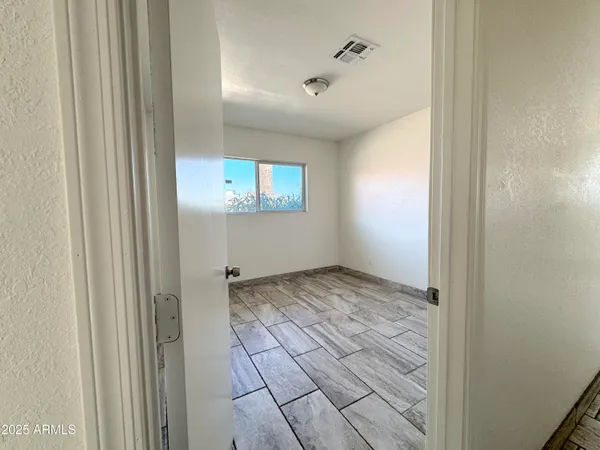 a view of a hallway with wooden floor and a bathroom