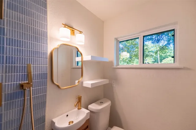 a white toilet sitting next to a bathroom sink and a vanity