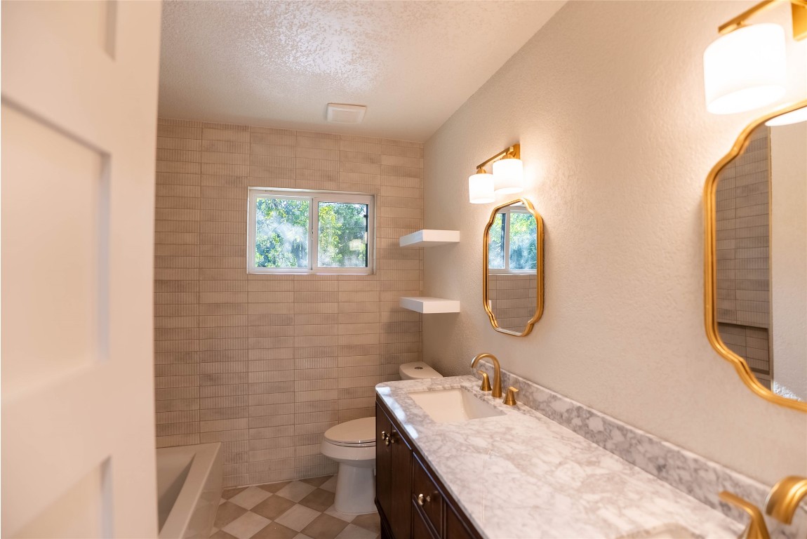 7700 Robalo Road Austin, TX 78757 - Photo 17 of 23 a bathroom with a granite countertop toilet sink and mirror