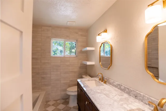 a bathroom with a granite countertop toilet sink and mirror