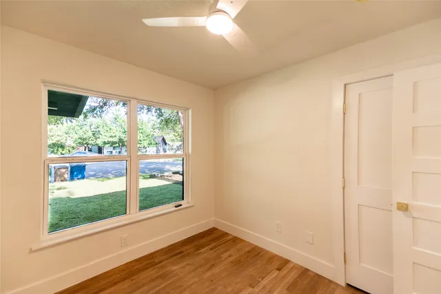 a view of an empty room with wooden floor and windows