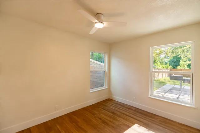 a view of an empty room with wooden floor and a window