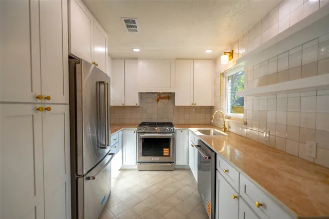 a large kitchen with stainless steel appliances granite countertop a refrigerator a sink and a stove