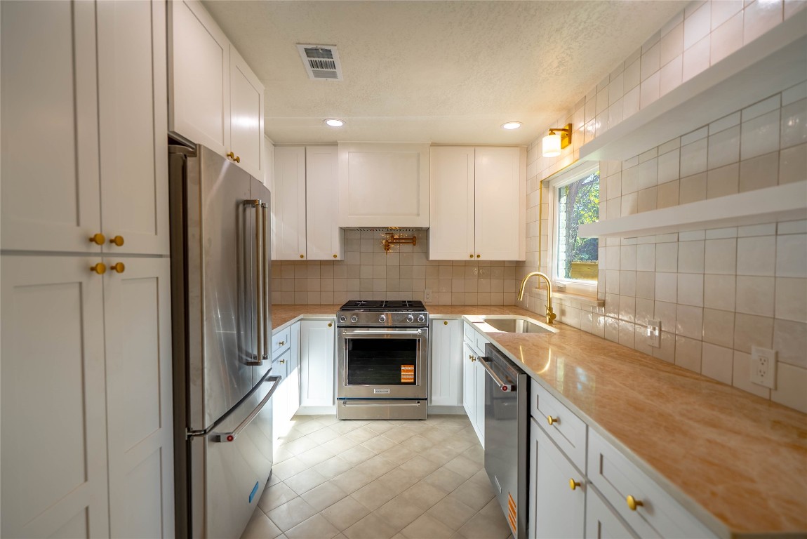 7700 Robalo Road Austin, TX 78757 - Photo 6 of 23 a large kitchen with stainless steel appliances granite countertop a refrigerator a sink and a stove