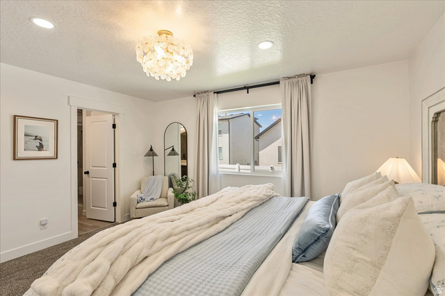 3916 South Sage Wood Avenue Mapleton, UT 84664 - Photo 16 of 33 Spacious bedroom featuring recessed lighting, a decorative ceiling fixture, a window with curtains, and a doorway opening to an additional area