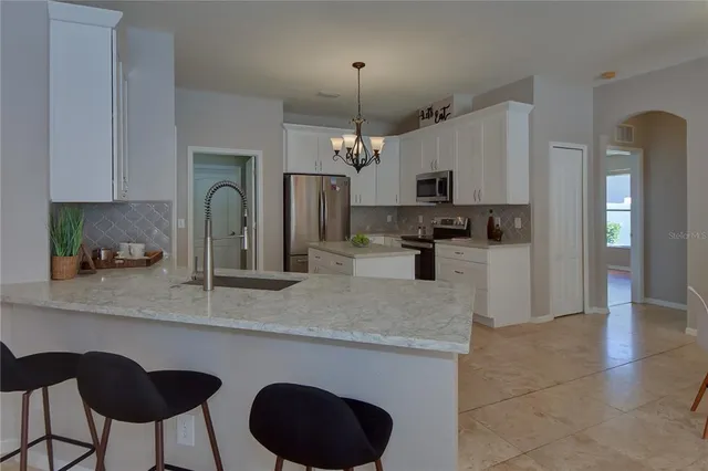 a kitchen with stainless steel appliances granite countertop a sink a stove top oven a refrigerator and a stove