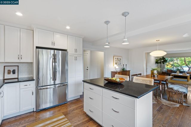 a kitchen with kitchen island a counter space a refrigerator a stove a dining table and chairs with wooden floor