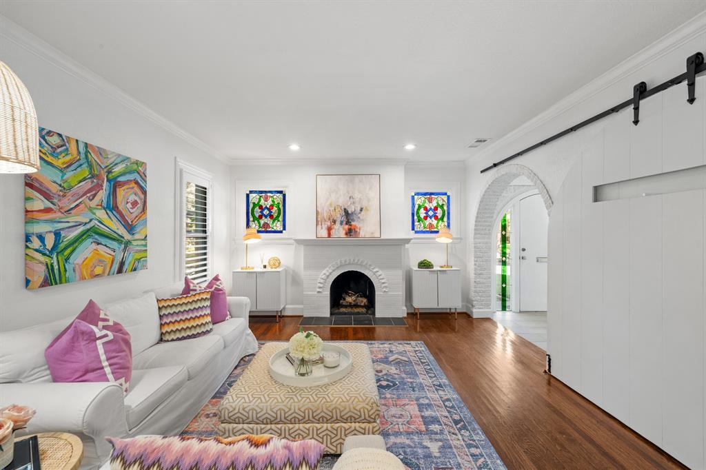 5242 Merrimac Avenue Dallas, TX 75206 - Photo 7 of 25 Living area with crown molding, wood finished floors, a brick fireplace, a barn door, and arched walkways