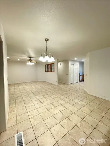 a view of an empty room with chandelier fan