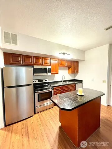 a kitchen with stainless steel appliances granite countertop a stove a sink and a refrigerator