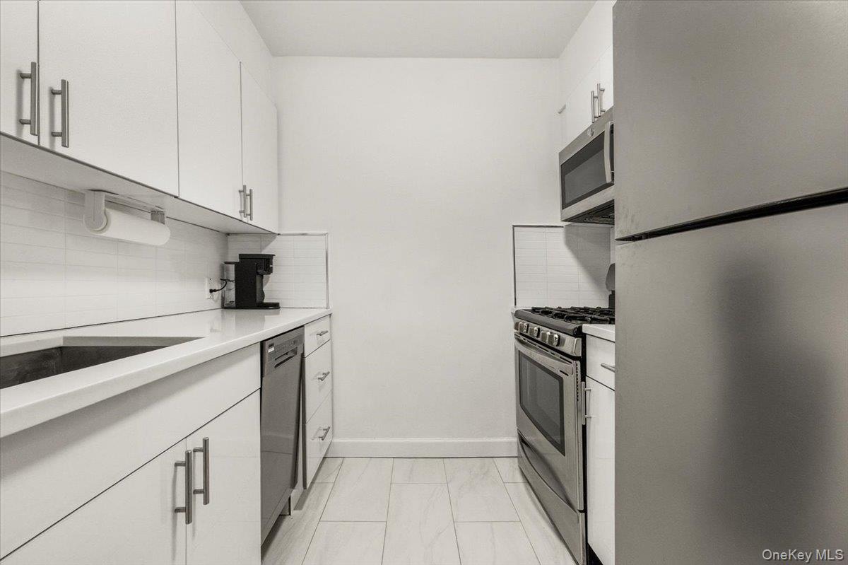 6 Birchwood Court, Unit 5B Mineola, NY 11501 - Photo 3 of 13 a kitchen with stainless steel appliances a refrigerator and a stove top oven