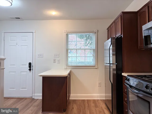 a kitchen with stainless steel appliances granite countertop a stove a sink dishwasher a refrigerator and a microwave oven with wooden floor