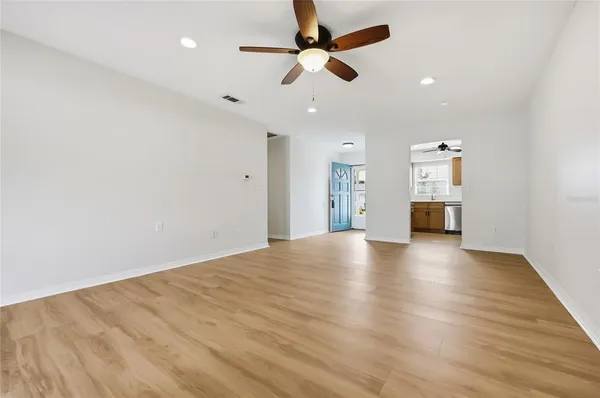 a view of empty room with wooden floor and ceiling fan