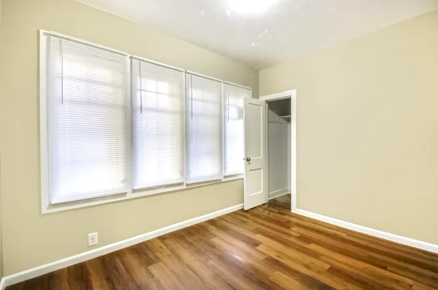 a view of an empty room with wooden floor and a window