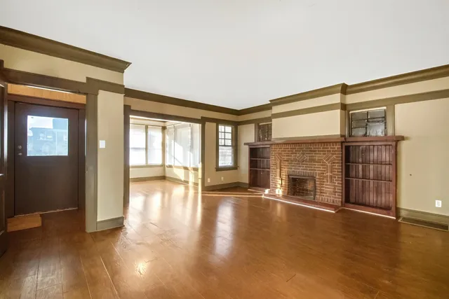a view of an empty room with wooden floor and a fireplace