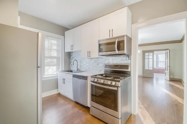 a kitchen with cabinets stainless steel appliances and wooden floor