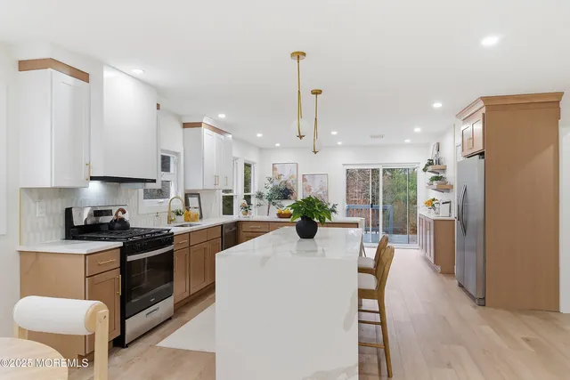 a kitchen with stainless steel appliances kitchen island granite countertop a refrigerator a stove a sink a dining table and chairs with wooden floor