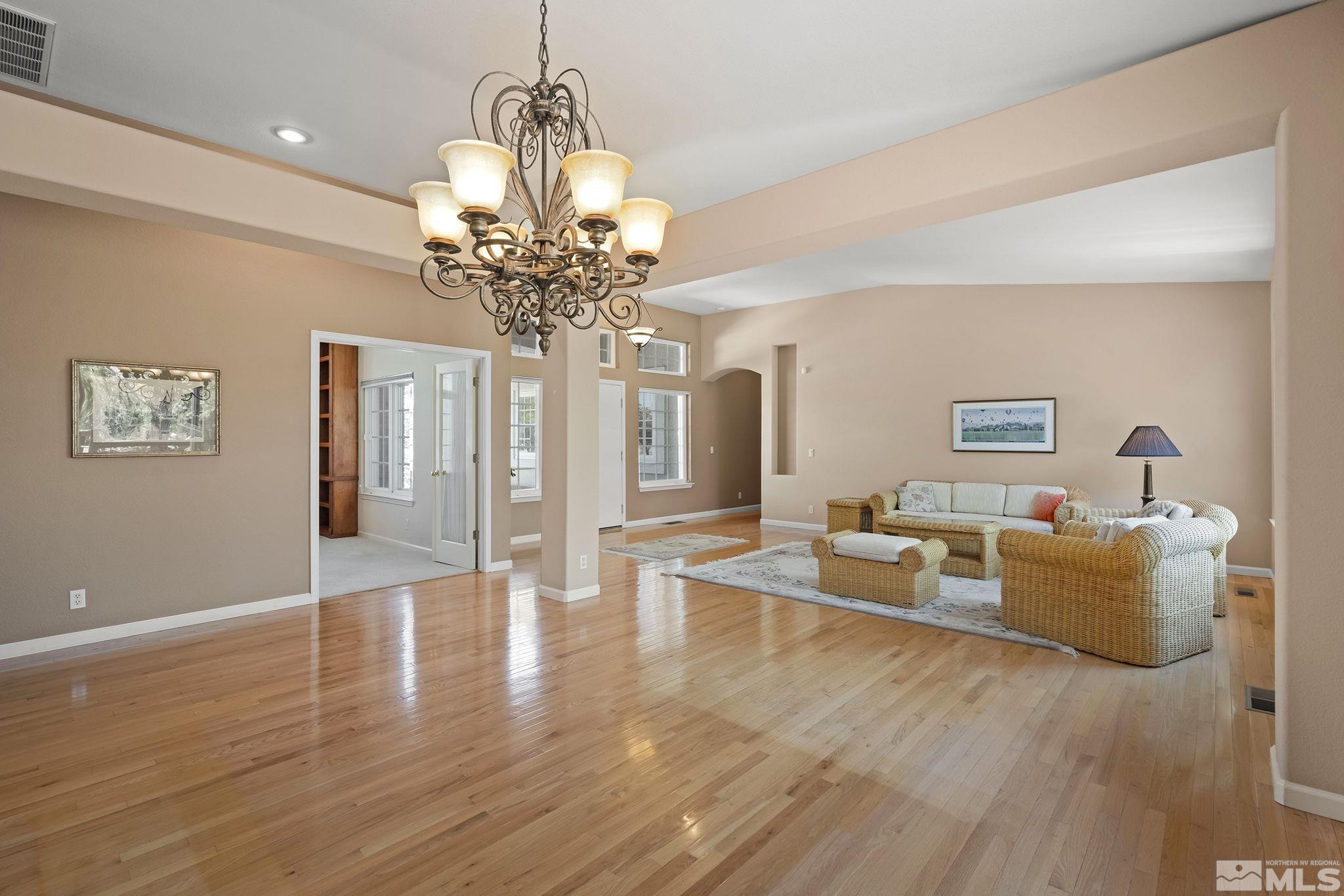 820 Flanders Road Reno, NV 89511 - Photo 9 of 40 a living room with couches chandelier and a dining table with wooden floor