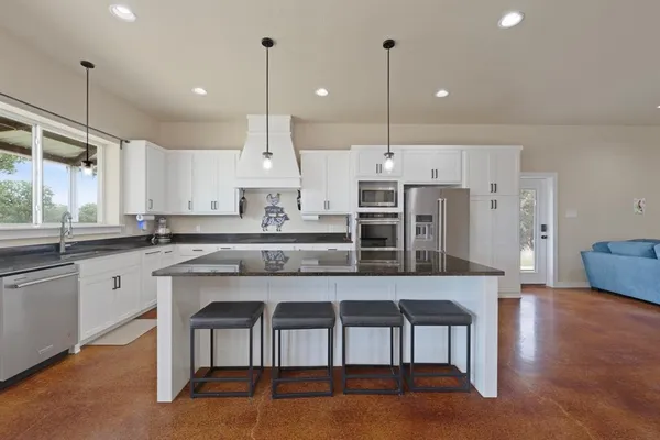 a kitchen with stainless steel appliances granite countertop a stove top oven a sink island and a refrigerator