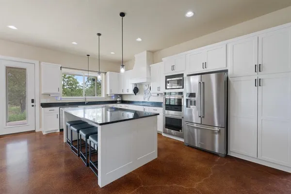a kitchen with stainless steel appliances granite countertop a refrigerator a sink and a stove