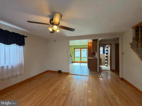 a view of empty room with wooden floor and fan
