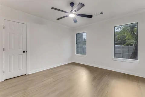 a view of an empty room with a window and wooden floor