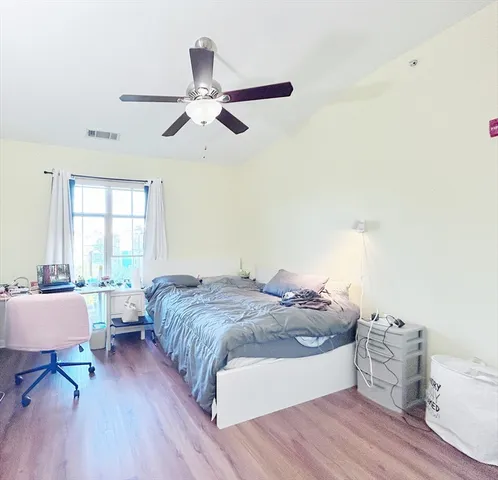 a spacious bedroom with a bed and wooden floor