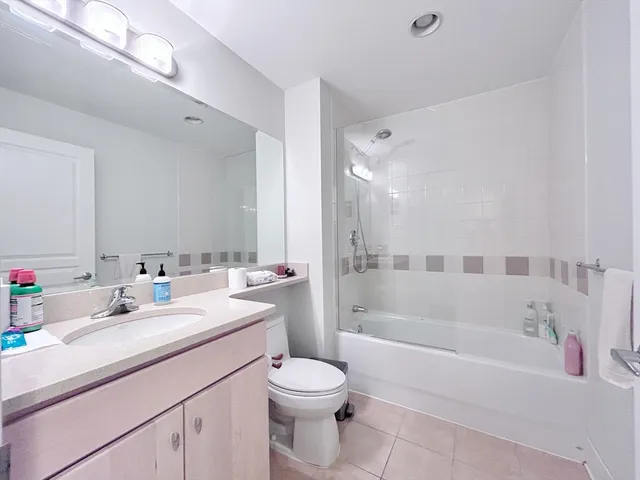 a bathroom with a bathtub shower sink vanity mirror and toilet