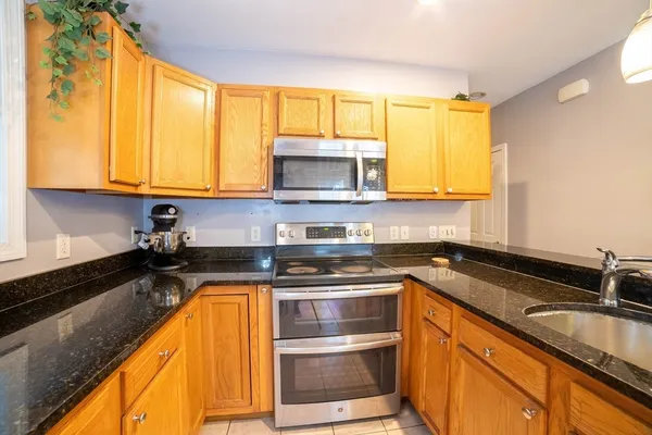 a kitchen with granite countertop a sink a counter top space and cabinets