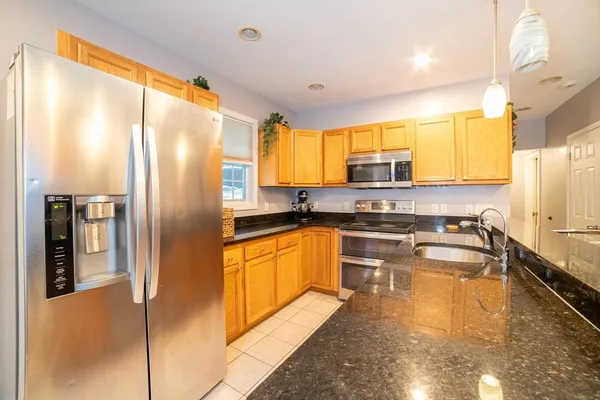 a kitchen with stainless steel appliances granite countertop a refrigerator a stove and a sink with wooden floor