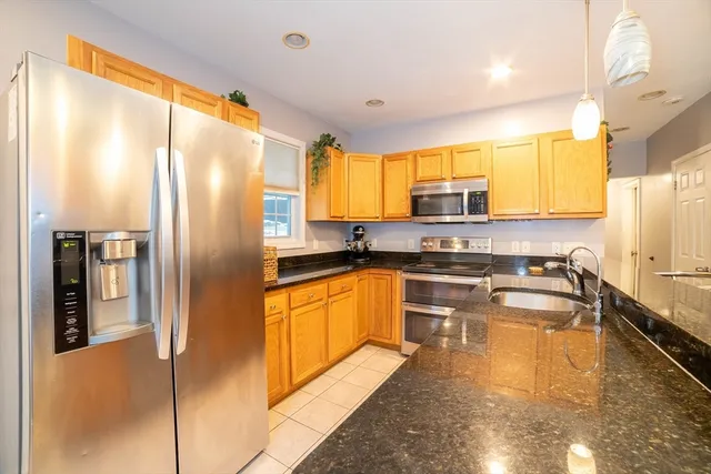 a kitchen with stainless steel appliances granite countertop a refrigerator a stove and a sink with wooden floor