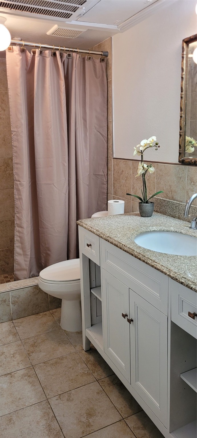 9031 Rue Cambon Street, Unit 69 Houston, TX 77074 - Photo 6 of 13 a bathroom with a granite countertop sink a toilet and a mirror