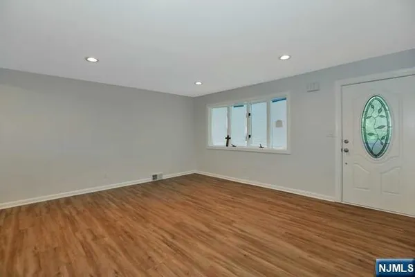 an empty room with wooden floor and mirror