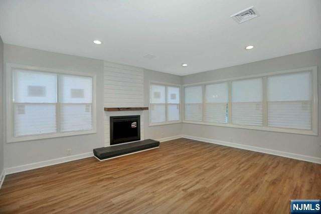 89 Wyoming Road Paramus, NJ 07652 - Photo 6 of 17 an empty room with wooden floor fireplace and windows
