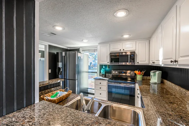 a kitchen filled with stainless steel appliances kitchen island granite countertop a sink and cabinets