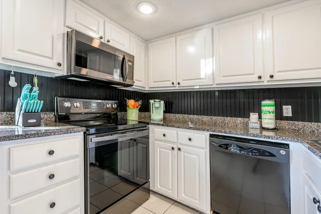 a kitchen with granite countertop a stove microwave and cabinets