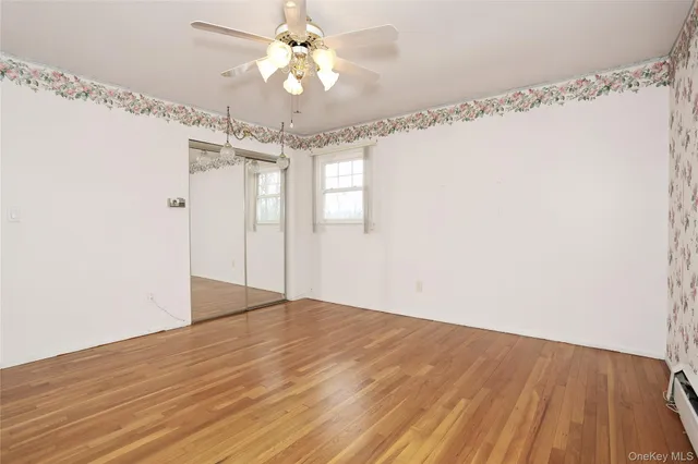 en empty room with wooden floor and ceiling fan