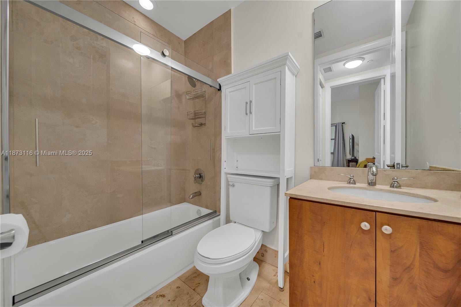 1607 Ponce De Leon, Unit 10C Coral Gables, FL 33134 - Photo 14 of 19 a bathroom with a granite countertop sink toilet and shower