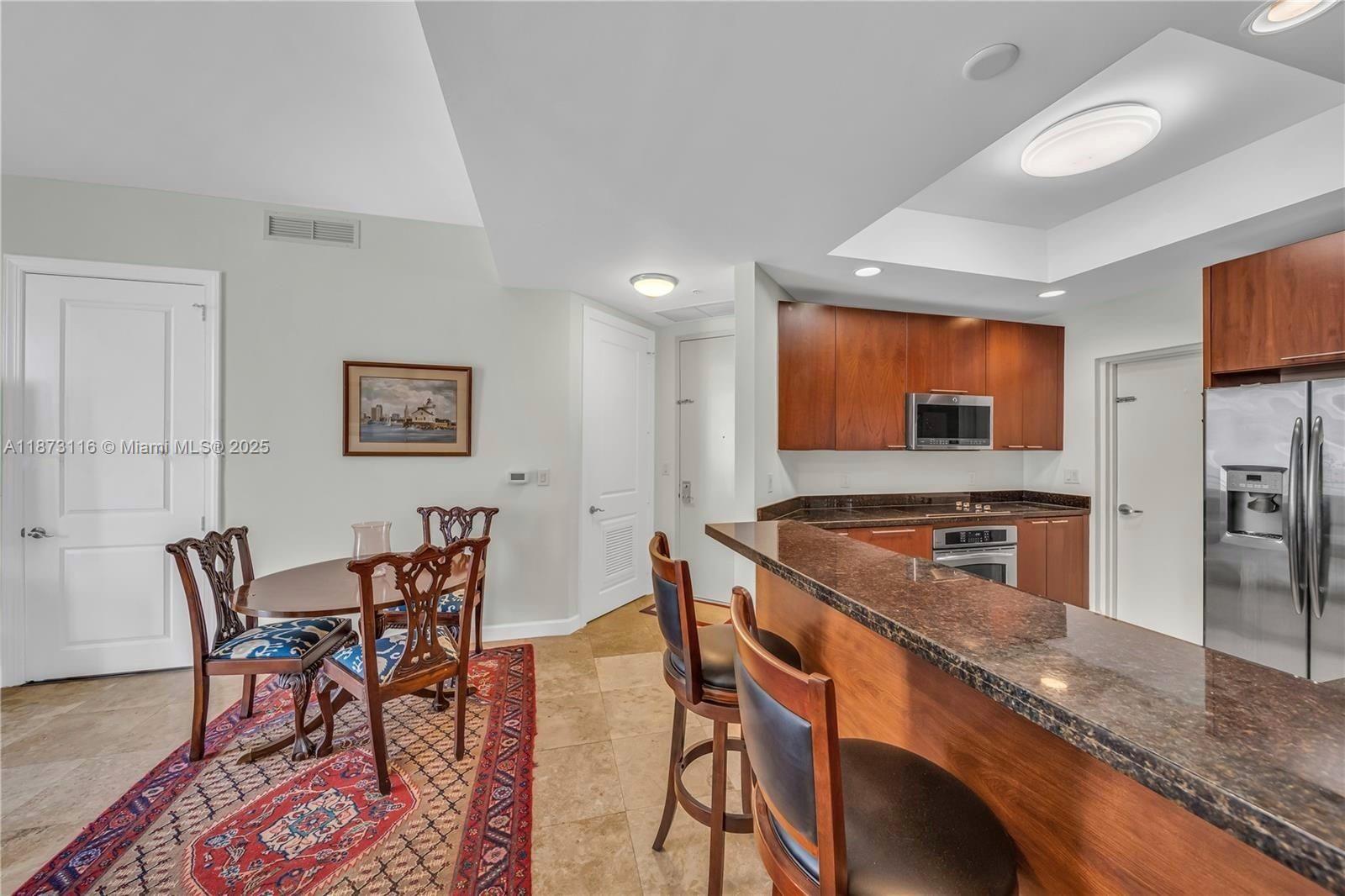 1607 Ponce De Leon, Unit 10C Coral Gables, FL 33134 - Photo 5 of 19 a kitchen with stainless steel appliances granite countertop a table and chairs in it