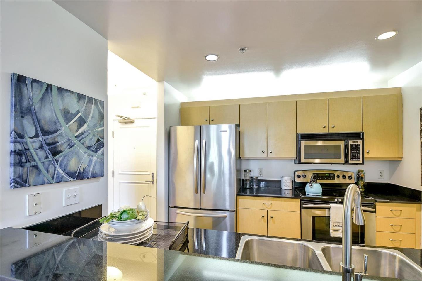 140 South Van Ness Avenue, Unit 422 San Francisco, CA 94103 - Photo 7 of 32 a kitchen with stainless steel appliances a stove a refrigerator and a fireplace