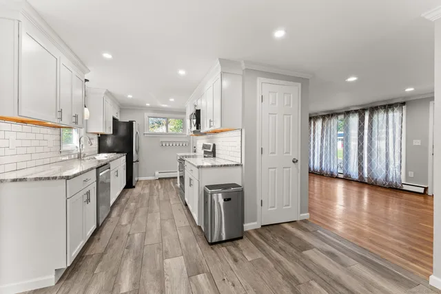a large kitchen with a center island wooden floor stainless steel appliances and cabinets
