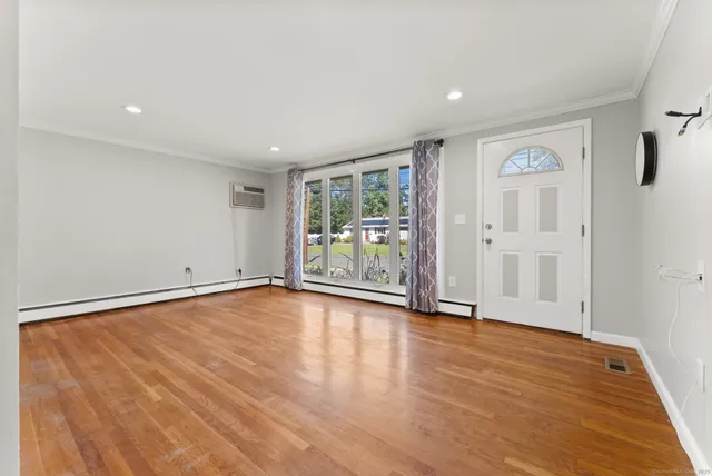 a view of an empty room with a window and wooden floor