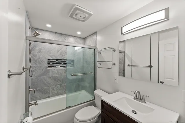 a bathroom with a shower sink vanity mirror and toilet