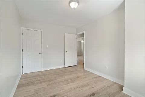 a view of an empty room with wooden floor and closet