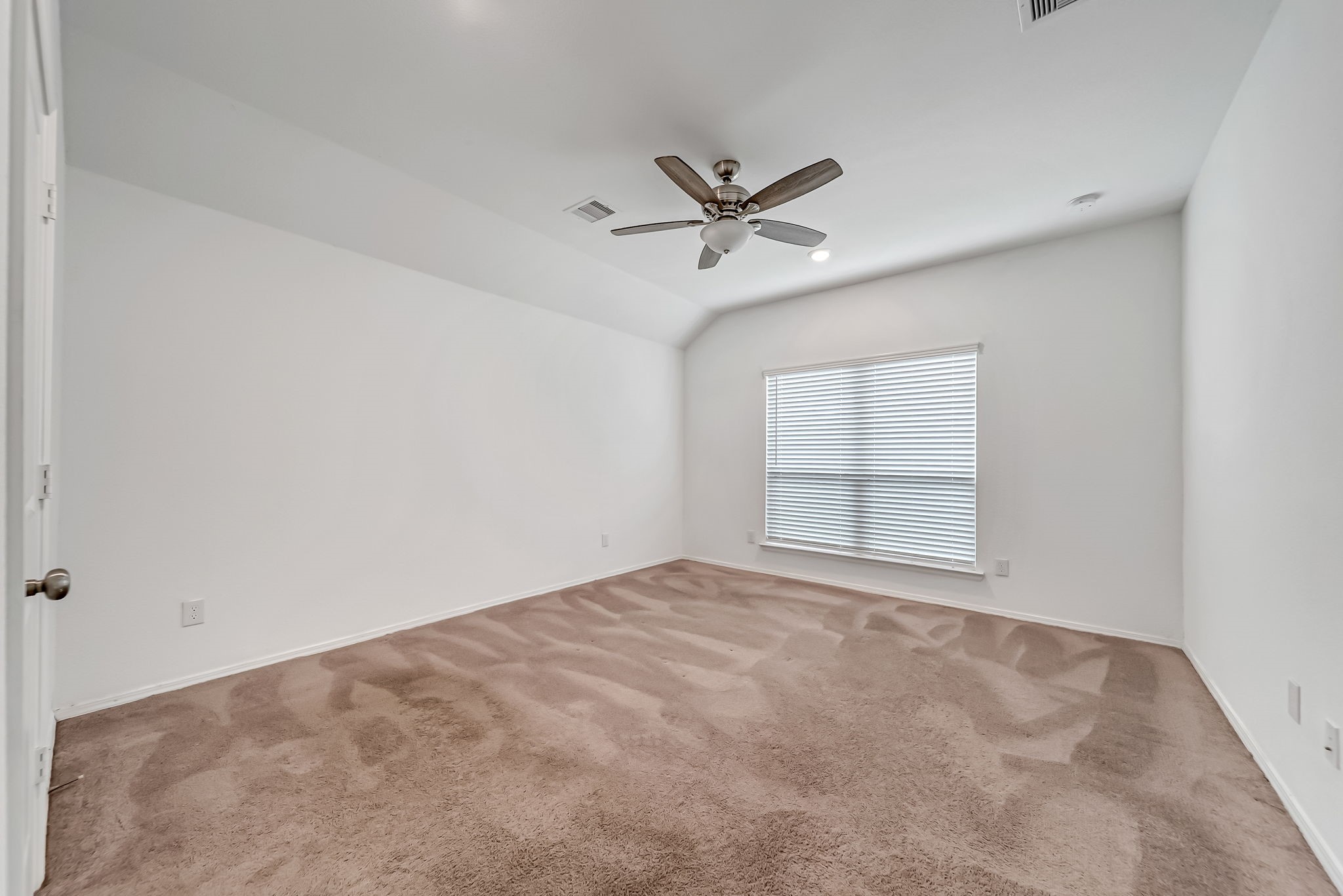 2847 Mistygate Court Conroe, TX 77301 - Photo 14 of 27 This spacious, well-lit room features neutral carpeting, a ceiling fan, and a large window with blinds, providing a comfortable and versatile space ideal for a bedroom or office.