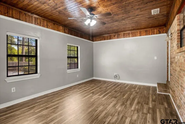 en empty room with wooden floor and windows